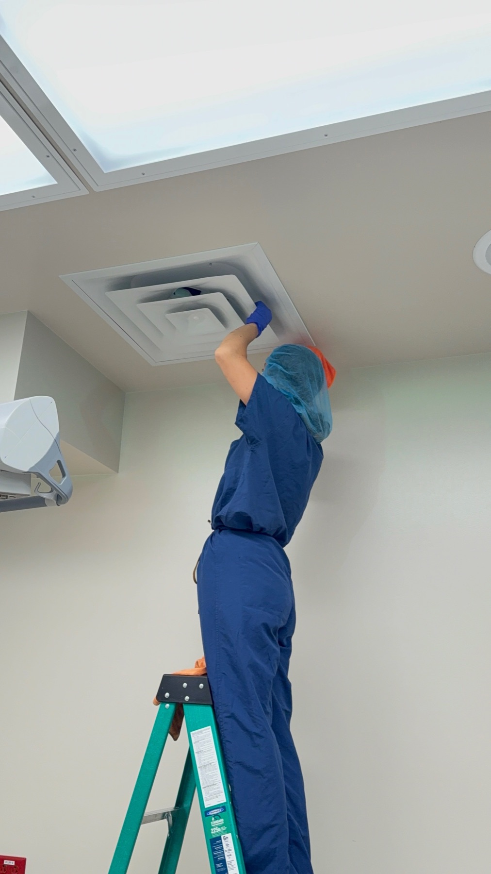 Technician reaching a ceiling HVAC diffuser