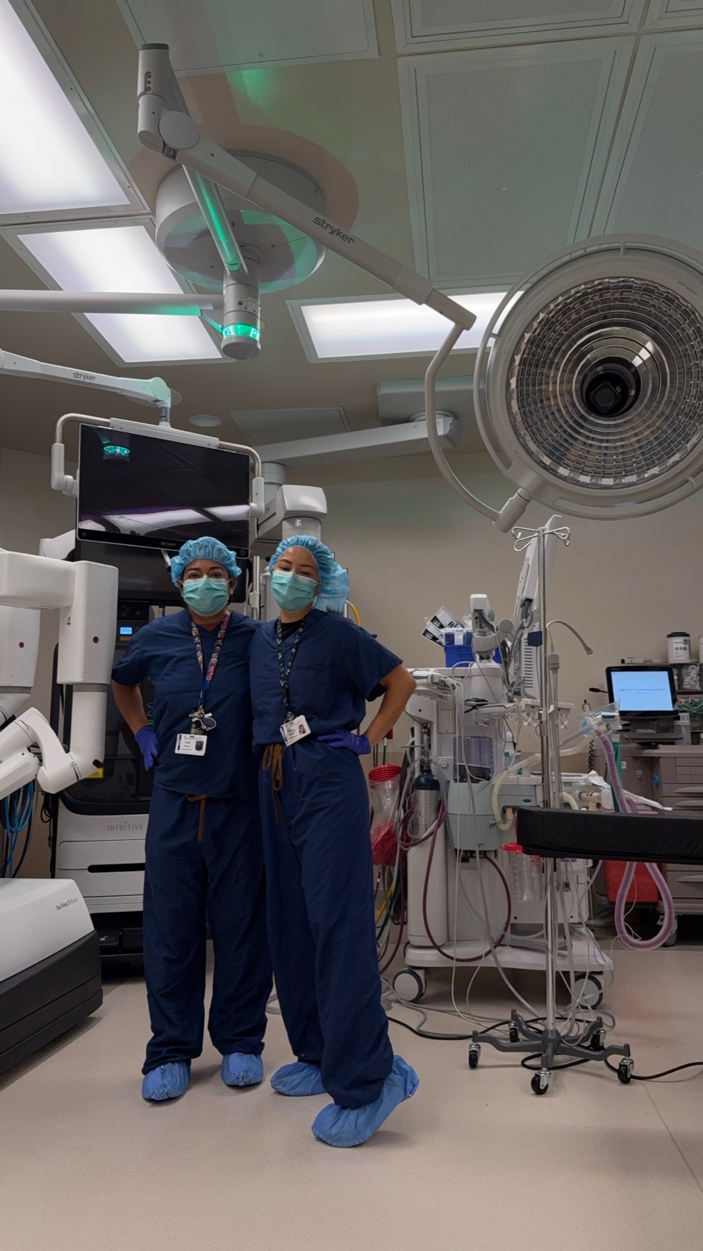 Two Vector technicians in a working operating room beside surgical robotics