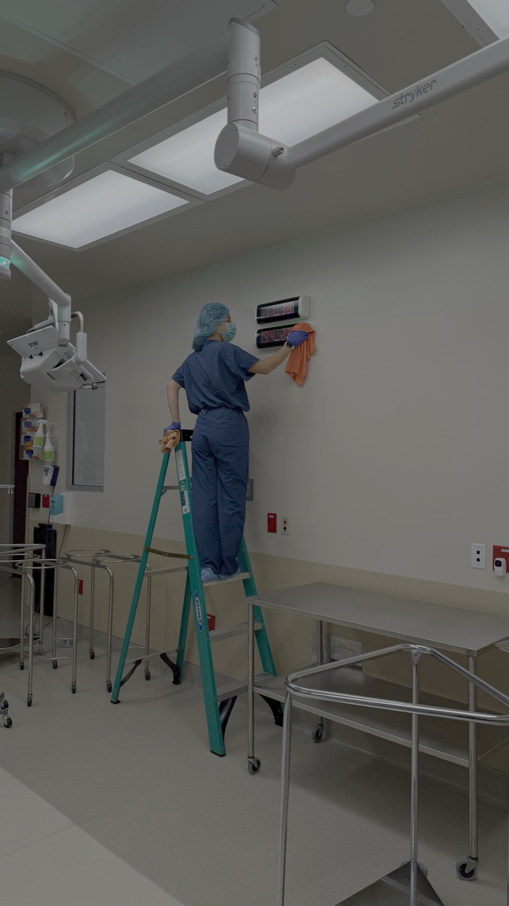 Technician cleaning above operating room equipment